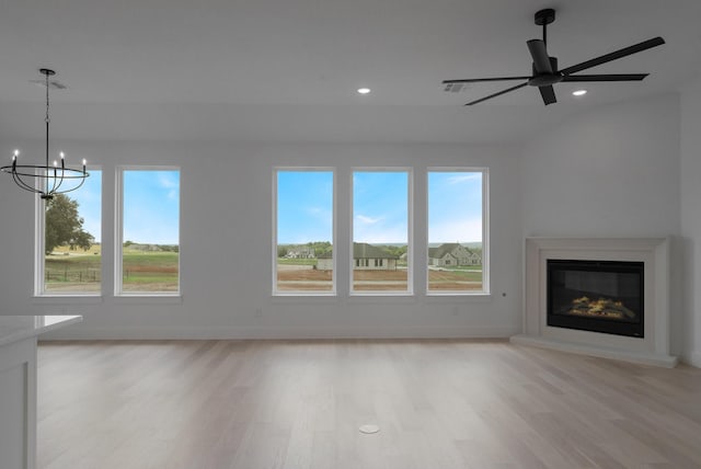 unfurnished living room featuring ceiling fan with notable chandelier and light wood-type flooring