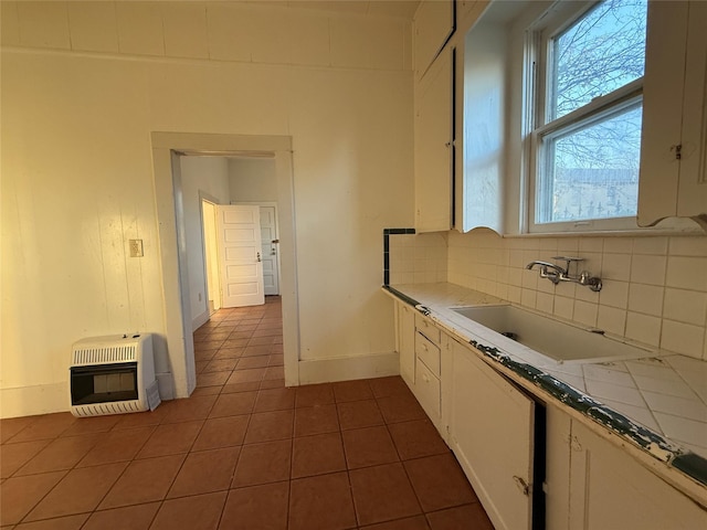 kitchen featuring tile countertops, sink, heating unit, and white cabinets