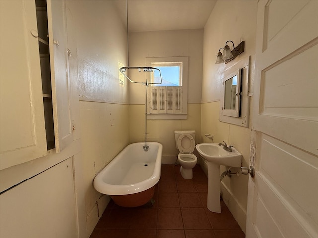 bathroom with a washtub, tile patterned flooring, and toilet