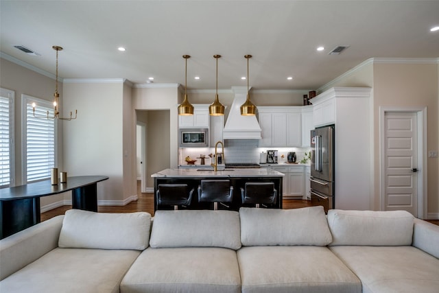 living room featuring hardwood / wood-style flooring, ornamental molding, sink, and a chandelier