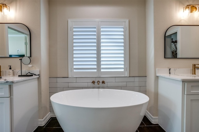 bathroom with tile patterned floors, a washtub, and vanity