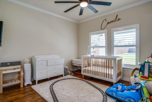 bedroom featuring ceiling fan, dark hardwood / wood-style floors, a crib, and crown molding