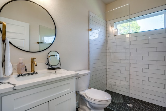 bathroom with vanity, toilet, and tiled shower