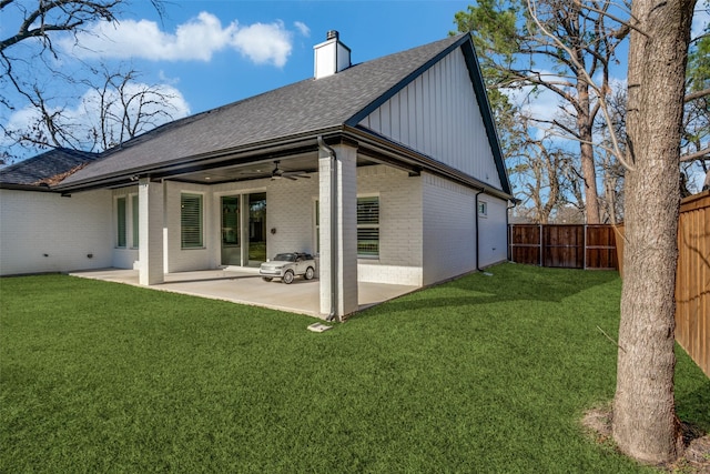 rear view of house with ceiling fan, a patio area, and a lawn