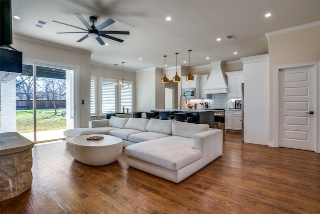 living room featuring ceiling fan, ornamental molding, and dark wood-type flooring