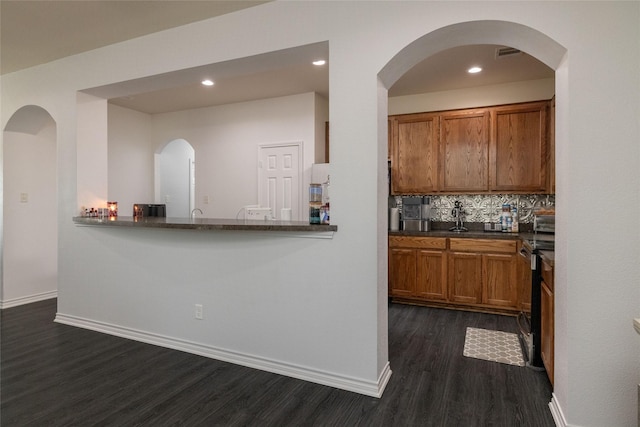 kitchen with kitchen peninsula, dark hardwood / wood-style flooring, and decorative backsplash