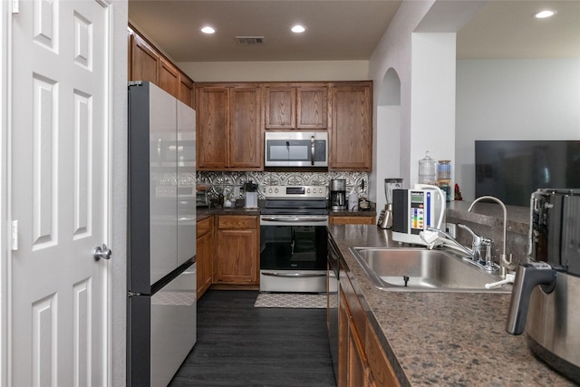 kitchen with sink, backsplash, dark wood-type flooring, and stainless steel appliances