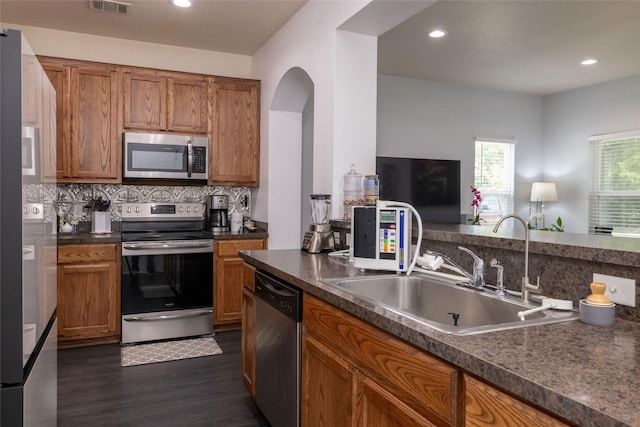 kitchen featuring dark wood-type flooring, appliances with stainless steel finishes, sink, and backsplash