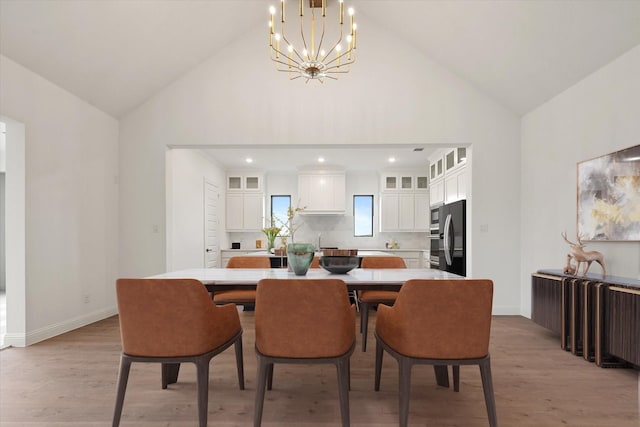 dining area with lofted ceiling, light wood-type flooring, sink, and a chandelier