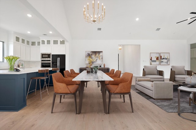 dining area featuring a notable chandelier, lofted ceiling, and light hardwood / wood-style flooring