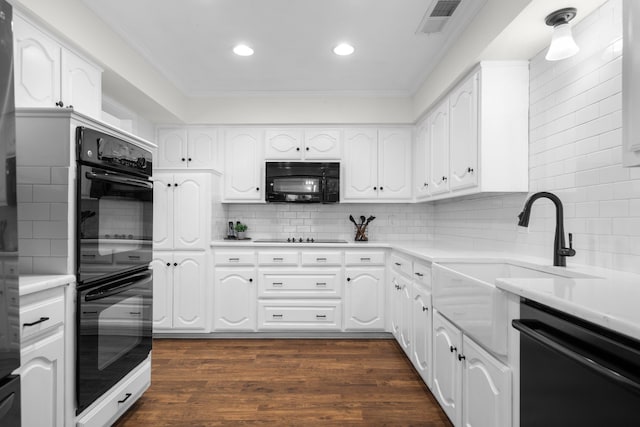 kitchen featuring black appliances, white cabinets, and backsplash