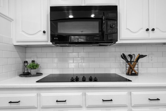 kitchen with black appliances, white cabinetry, and tasteful backsplash