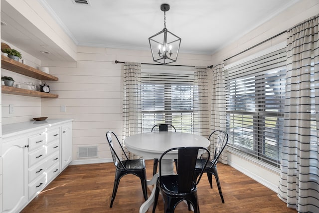 dining room featuring dark hardwood / wood-style floors, crown molding, and a notable chandelier