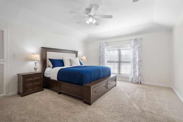 bedroom with ceiling fan, light carpet, and a tray ceiling