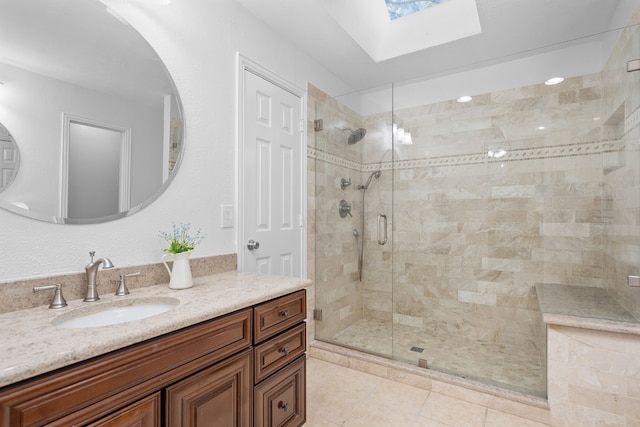 bathroom with tile patterned floors, vanity, a shower with door, and a skylight