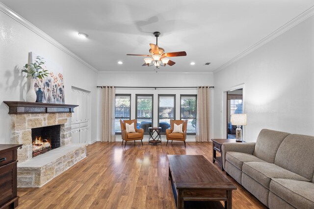 living room with ceiling fan, a fireplace, hardwood / wood-style floors, and ornamental molding