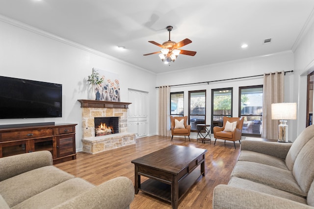 living room with crown molding, a fireplace, ceiling fan, and hardwood / wood-style floors