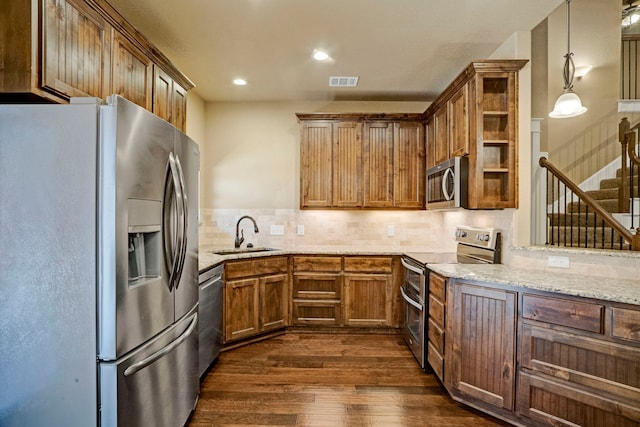 kitchen featuring pendant lighting, sink, dark wood-type flooring, stainless steel appliances, and tasteful backsplash