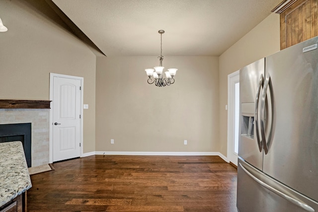 kitchen with pendant lighting, stainless steel fridge, dark hardwood / wood-style flooring, a notable chandelier, and light stone countertops