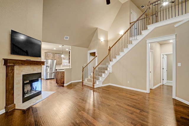 unfurnished living room with hardwood / wood-style flooring, a multi sided fireplace, and a high ceiling