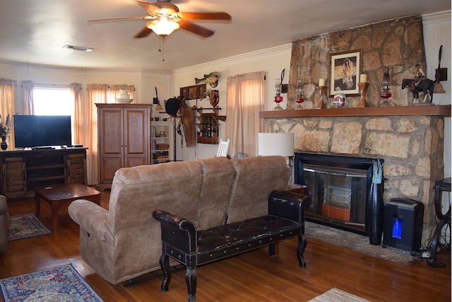 living room featuring hardwood / wood-style floors, a stone fireplace, ornamental molding, and ceiling fan