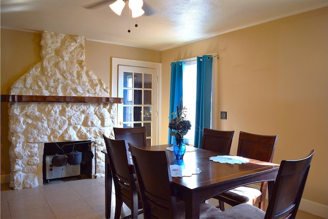 tiled dining space featuring crown molding, a stone fireplace, a textured ceiling, and ceiling fan