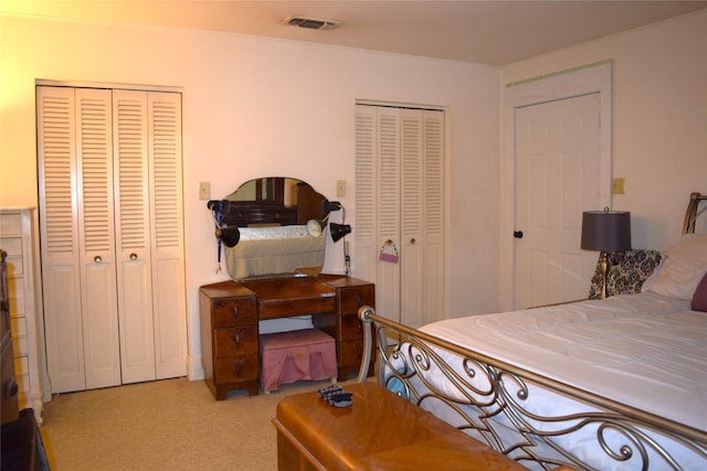 bedroom with multiple closets and light colored carpet