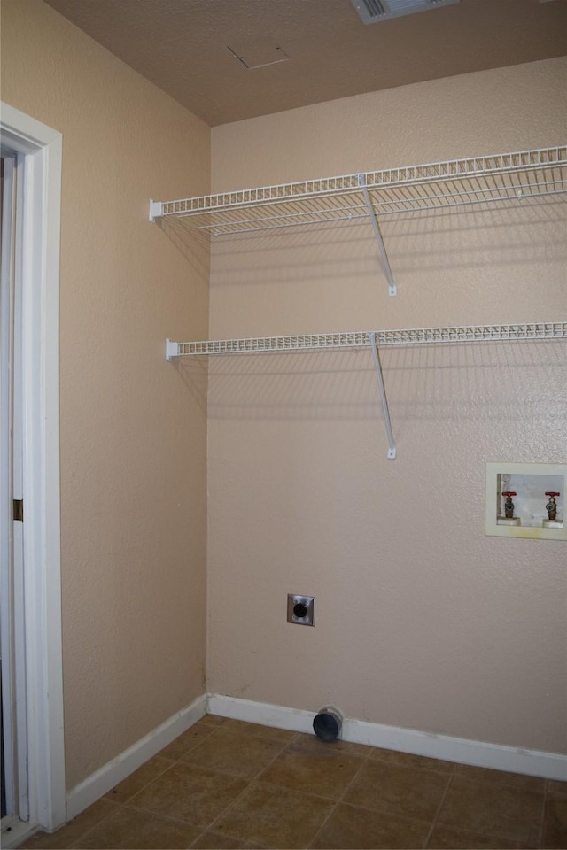 laundry room with electric dryer hookup, washer hookup, and dark tile patterned flooring