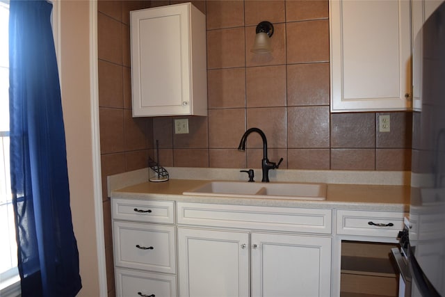 kitchen featuring white cabinetry, sink, decorative backsplash, and tile walls