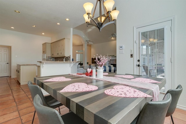 tiled dining space with ceiling fan with notable chandelier, ornate columns, and sink