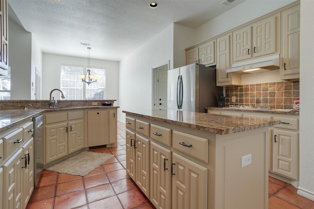 kitchen featuring appliances with stainless steel finishes, tasteful backsplash, cream cabinets, a center island, and hanging light fixtures