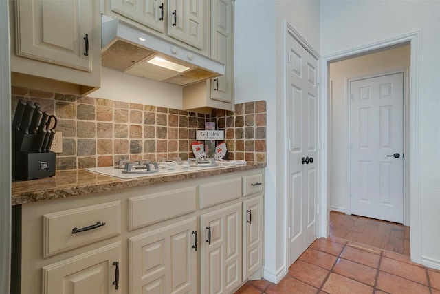 kitchen featuring stone counters, cream cabinetry, backsplash, and white gas cooktop