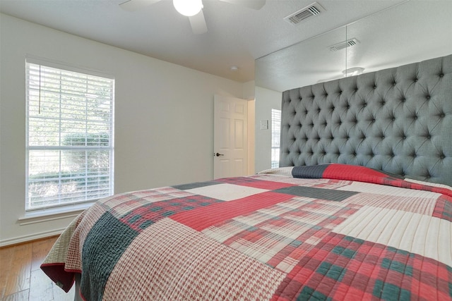 bedroom featuring multiple windows, ceiling fan, and hardwood / wood-style flooring