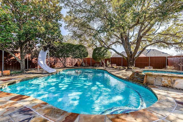 view of pool with an in ground hot tub, a patio area, and a water slide