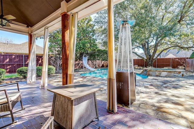 view of patio / terrace featuring ceiling fan and a swimming pool with hot tub