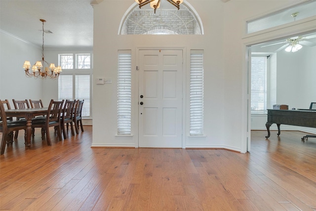 foyer featuring ornamental molding, ceiling fan with notable chandelier, and hardwood / wood-style flooring