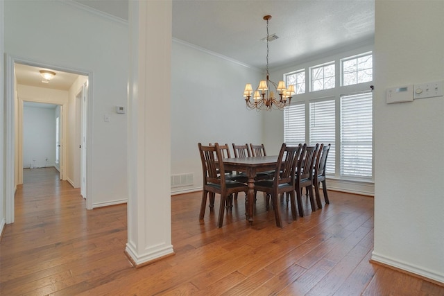 dining area featuring wood-type flooring, crown molding, and a chandelier