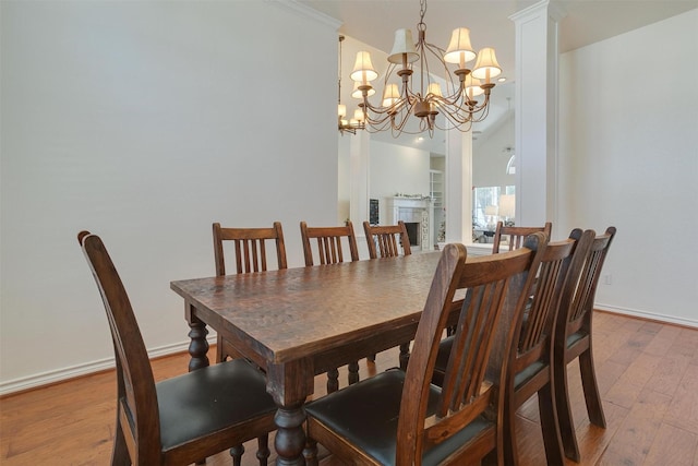 dining space with light hardwood / wood-style floors, decorative columns, ornamental molding, and an inviting chandelier