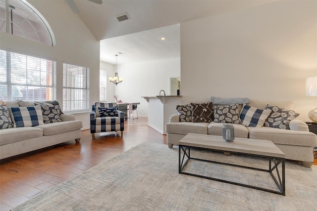 living room featuring hardwood / wood-style flooring, ceiling fan with notable chandelier, and high vaulted ceiling