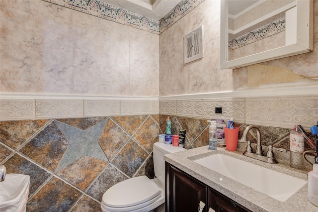 bathroom with vanity, toilet, and tile walls