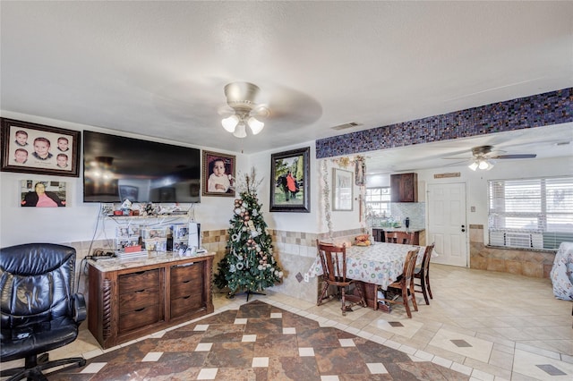 dining area with a textured ceiling, ceiling fan, light tile patterned flooring, and tile walls