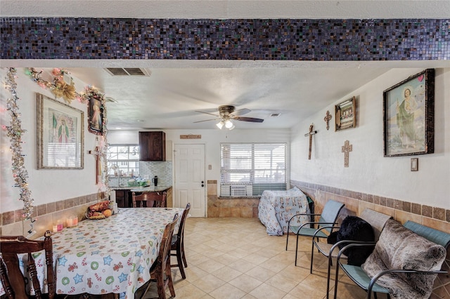 tiled dining space with a textured ceiling and ceiling fan