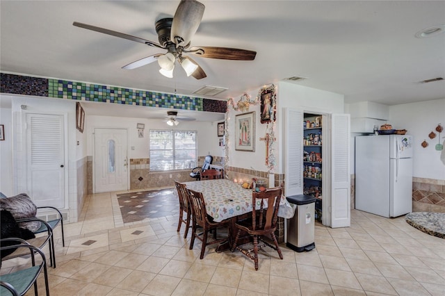 tiled dining room featuring ceiling fan and tile walls