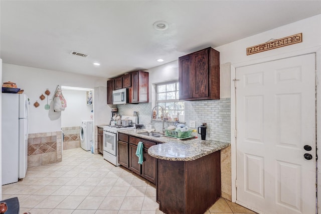 kitchen with light stone countertops, sink, washer / clothes dryer, white appliances, and light tile patterned floors