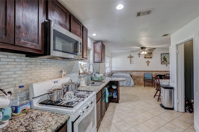 kitchen with sink, ceiling fan, light stone counters, light tile patterned flooring, and white range oven