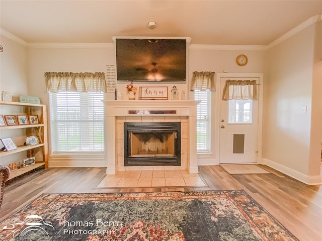 unfurnished living room featuring a tiled fireplace, crown molding, and wood-type flooring