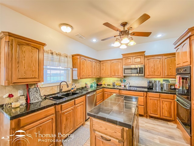 kitchen with tasteful backsplash, appliances with stainless steel finishes, sink, and a kitchen island