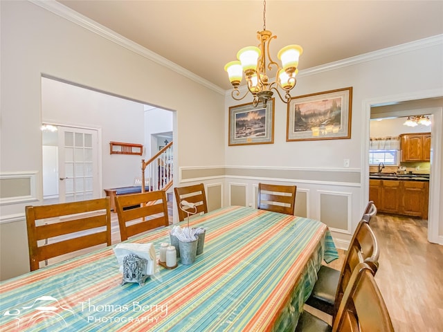 dining area with crown molding, light hardwood / wood-style flooring, and an inviting chandelier