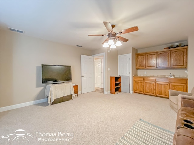 living room featuring ceiling fan, sink, and light colored carpet