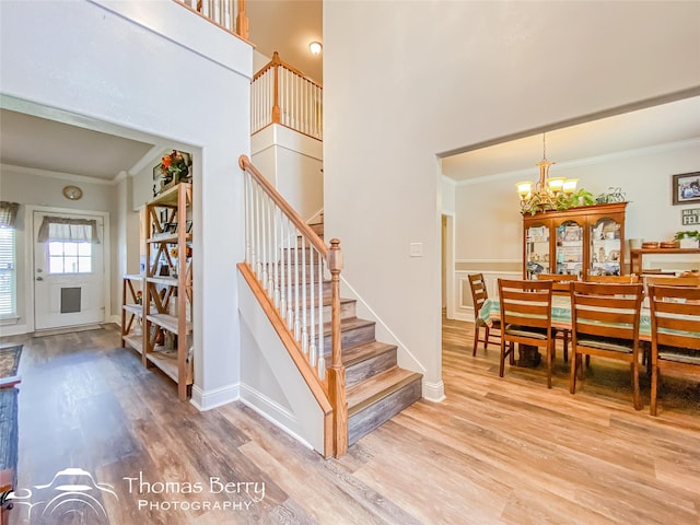 staircase featuring hardwood / wood-style floors, an inviting chandelier, and crown molding